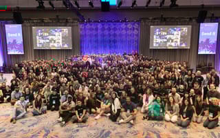 Huntress team members wearing branded T-shirts pose for a group photo in a conference center